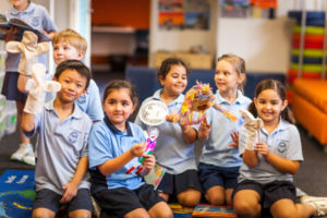 Students playing with puppets in colourful school library