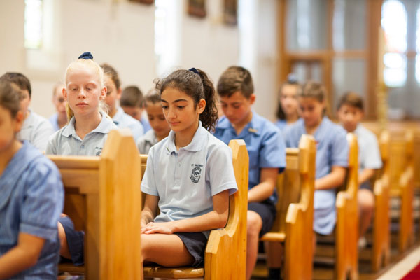 Students sitting in prayer inside church