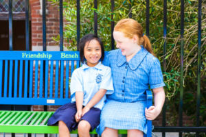 Year 6 and Kindy student sitting on a bench chatting