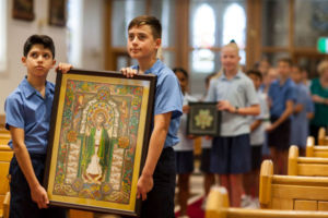 Students carrying framed artwork of St Patrick in a church procession